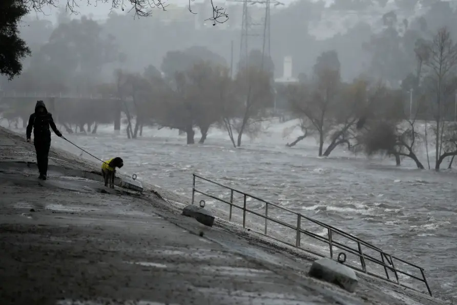 A man walking his dog on the edge of the Los Angeles River in the city on Sunday.Credit...Damian Dovarganes/Associated Press